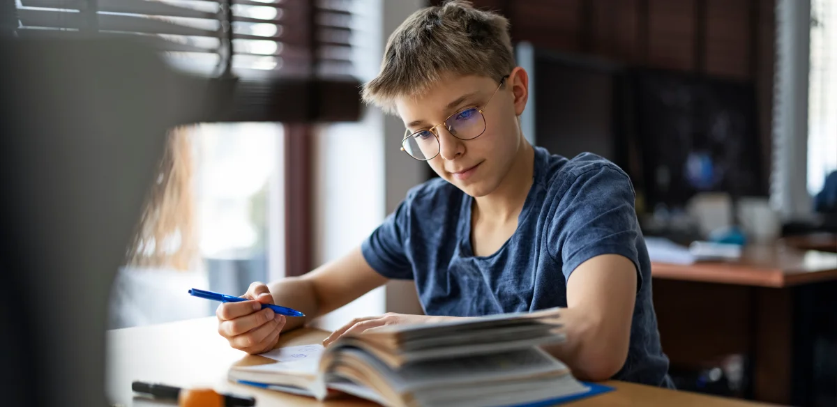 Middle school student wearing glasses and taking notes